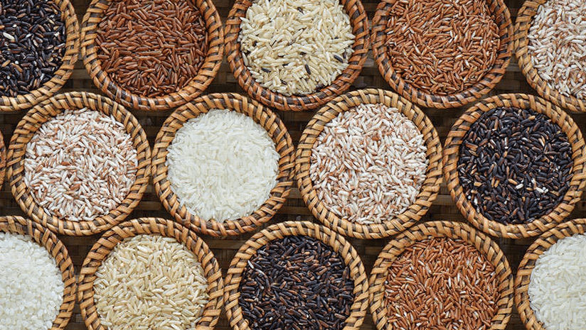Multiple woven baskets filled with different varieties of rice, including white, brown, red, and black rice, arranged in a neat pattern.